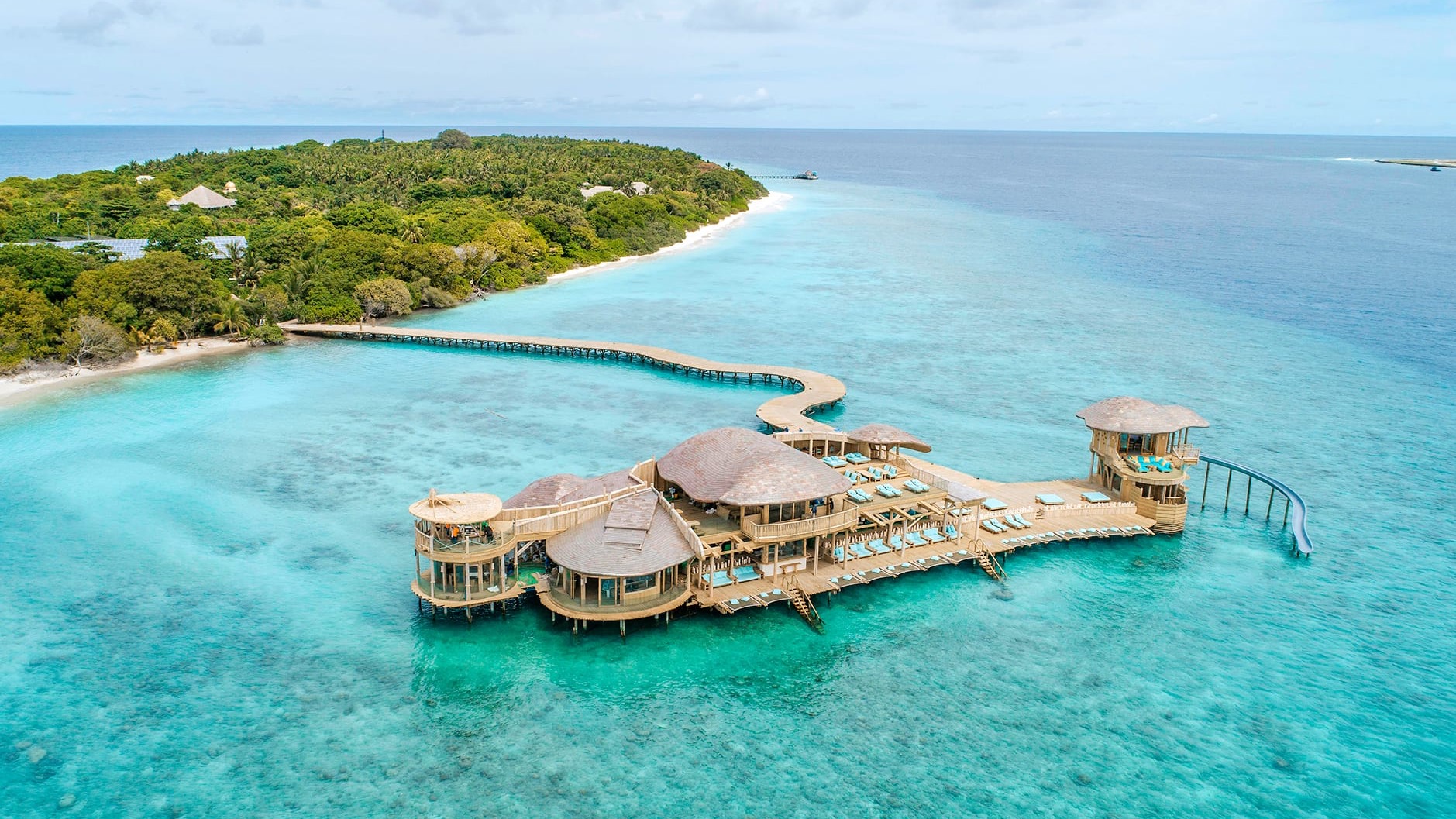 Bird view of large on water wodden building with water slider, sunbeds, and lunch area at Soneva Fushi, Noonu Atoll.