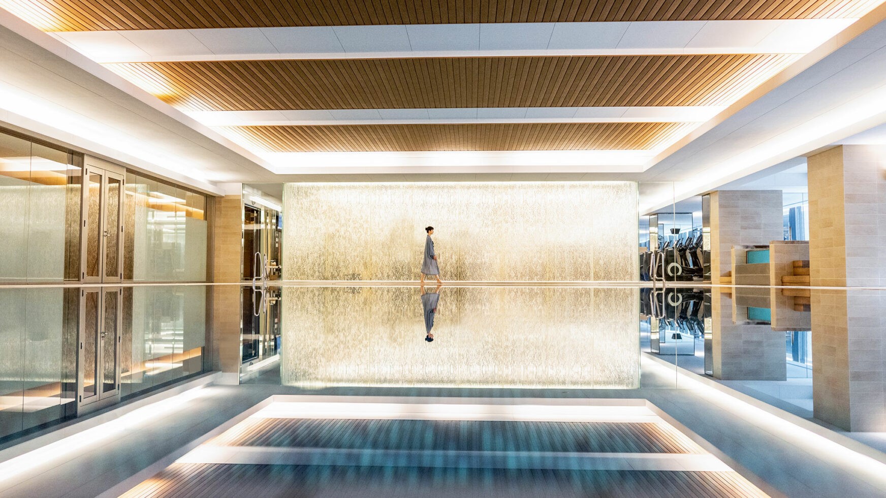 InterContinental pool/spa area with a woman in grey towel suit walking and gym to the right at InterContinental Osaka.