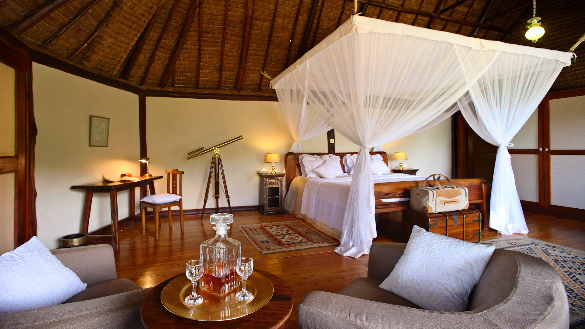 Suite with white bed, two chairs and wooden seiling