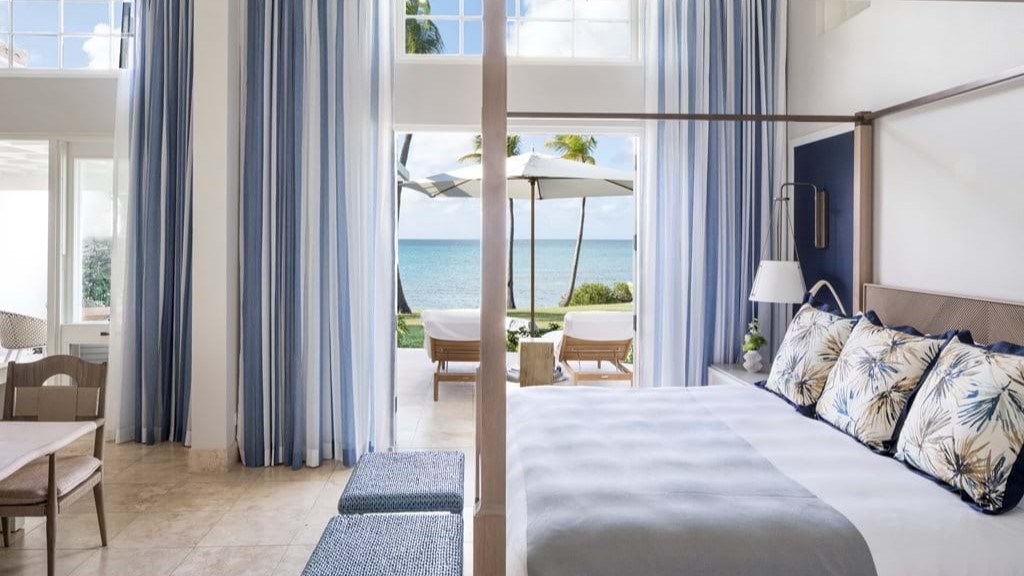 Suite with white bed and view of the ocean