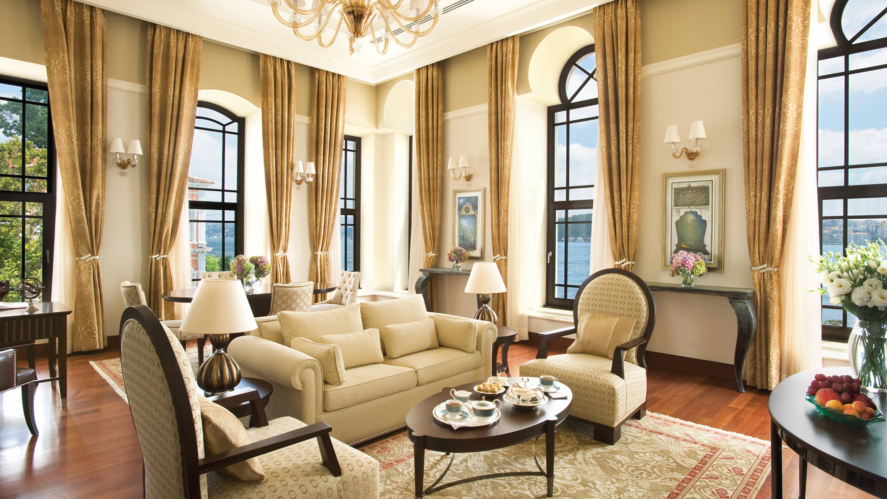 Suite at The Exquisite Four Seasons Istanbul At The Bosphorus offering a spacious living room with a comfortable interior design, couches and grand windows offering sights of the river and garden