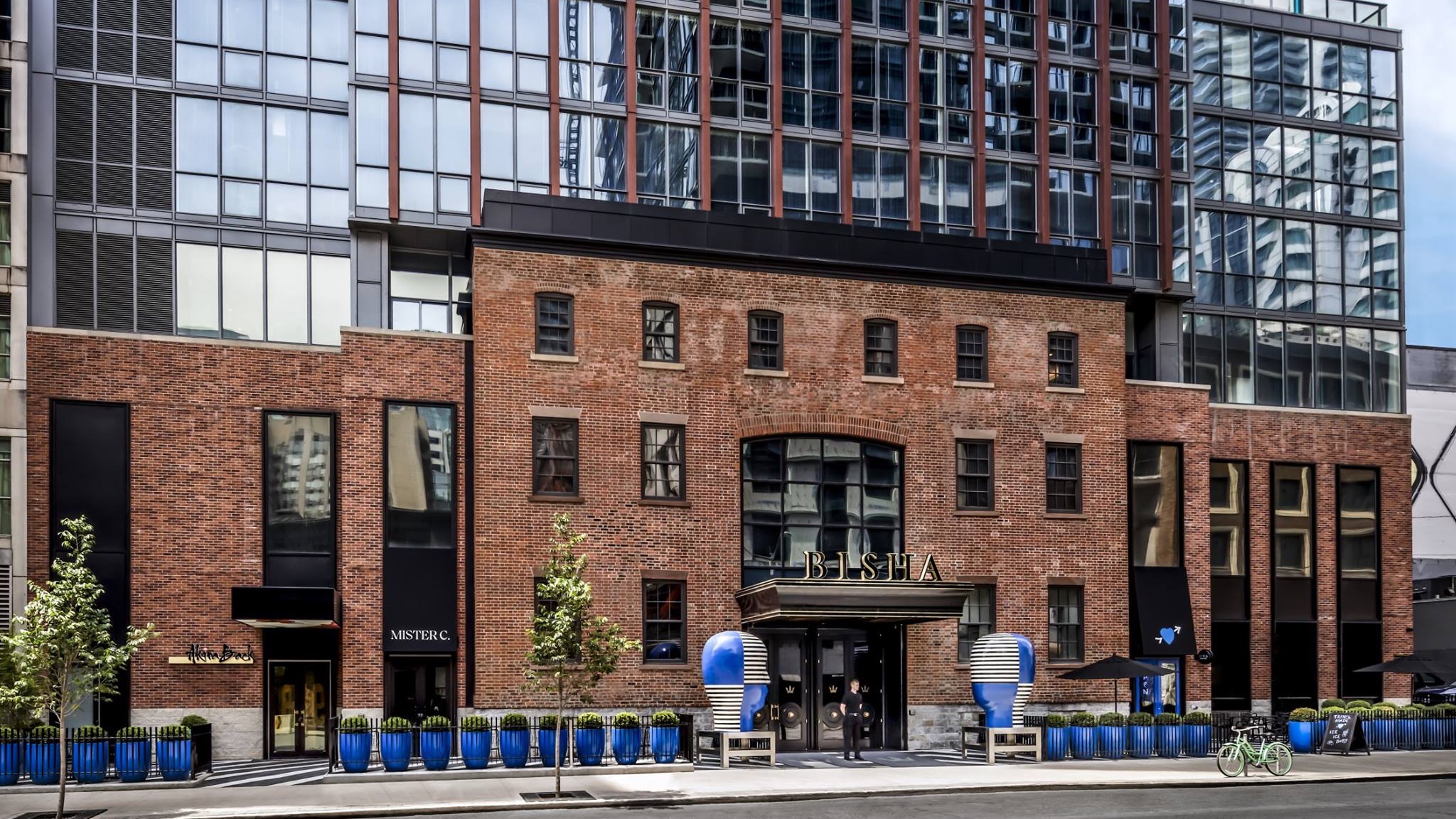 The outside and main entrance of Bisha hotel toronto Made of brick with a doorman by the door