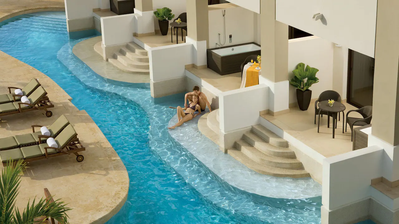 a couple relaxing in Secrets Wild Orchid Montego Bay's swimming pool in front of their rooms