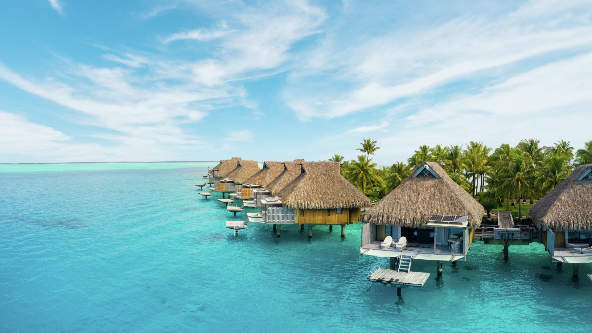 Wood cabins, clear water, palm trees and clear water in Conrad Bora Bora Nui.