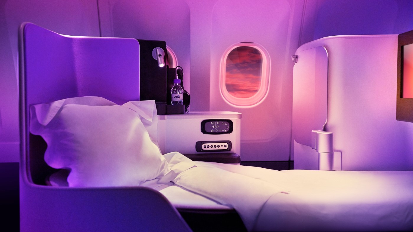 Bed with purple lighting and white sheets at businessclass flight