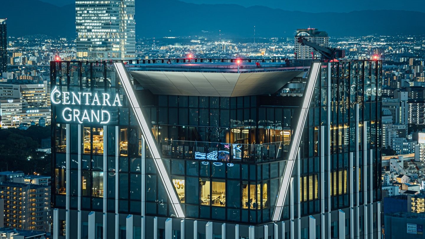 Large and wide glass building with helicopter pad at the top and white sign saying: CENTARA GRAND.