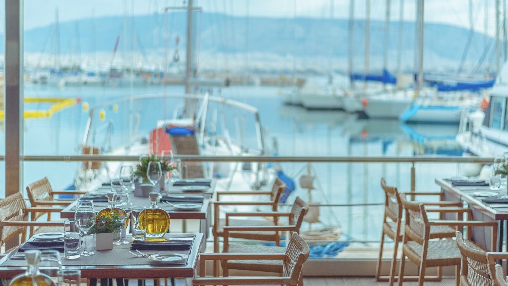 Varoulko Seaside resturant. A indoor resturant by the sea with tree chairs and large glass windows.