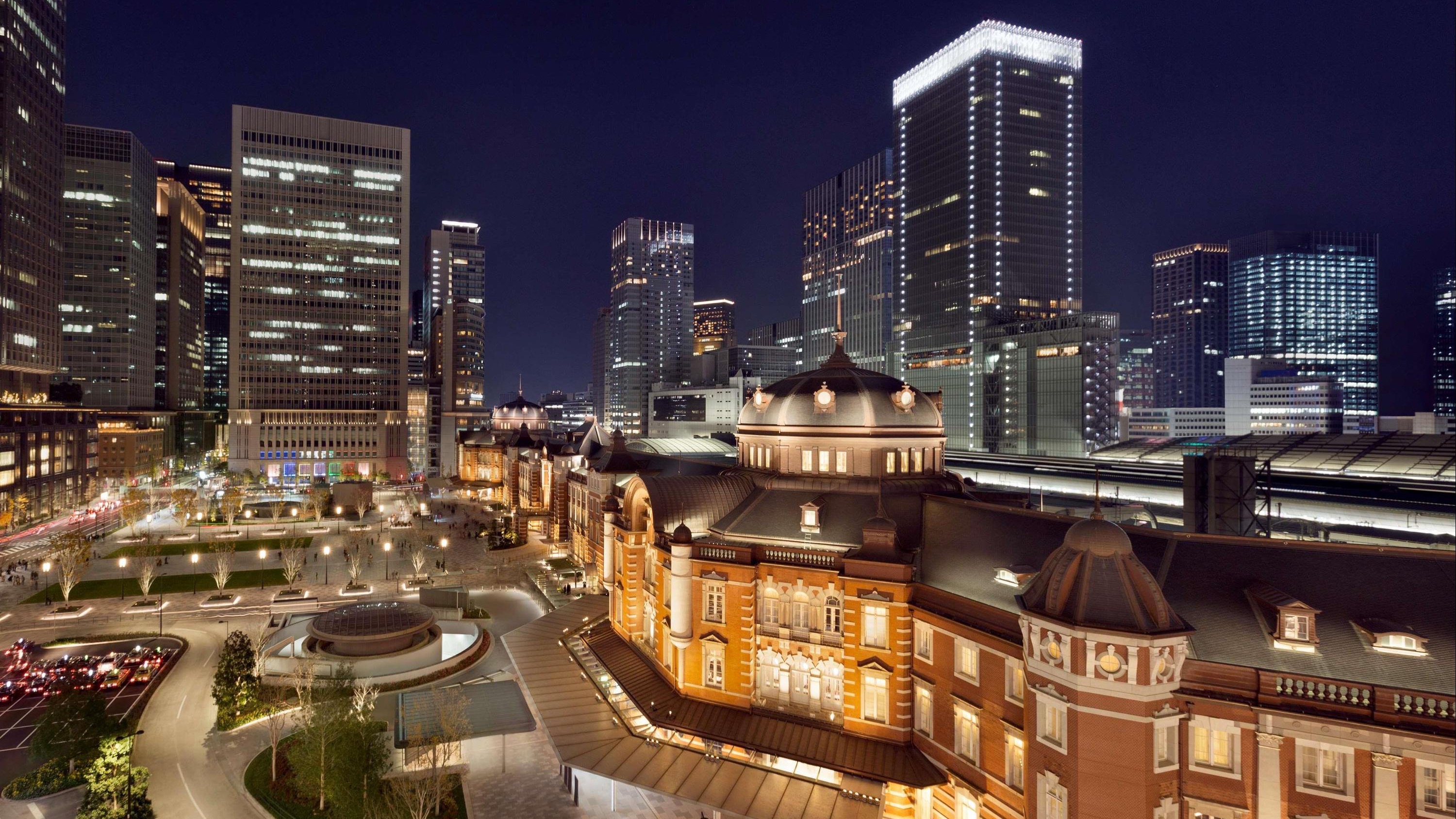 Long biulding with classic design, yellow and brown looking colours and grey rooftops.