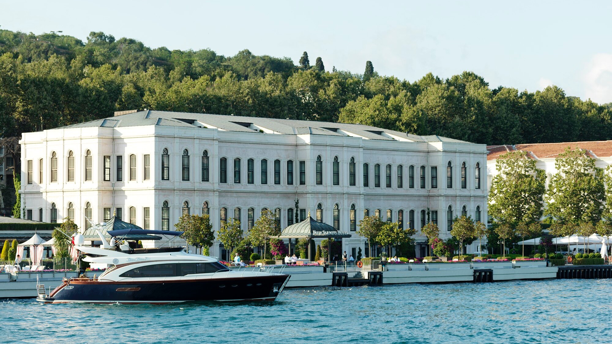 Impressive waterfront view of The Exquisite Four Seasons Hotel Istanbul At The Bosphorus offering a livley feel with it's all-white design, garden and view of the river
