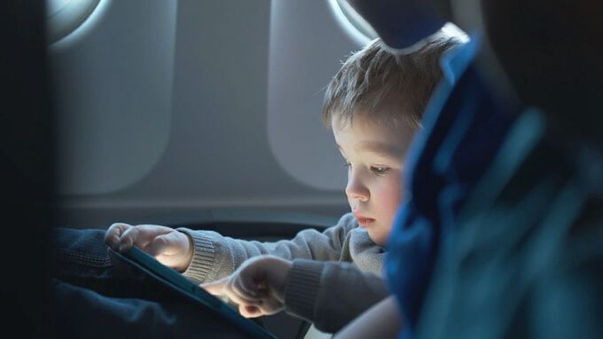 a toddler with his screen in business class