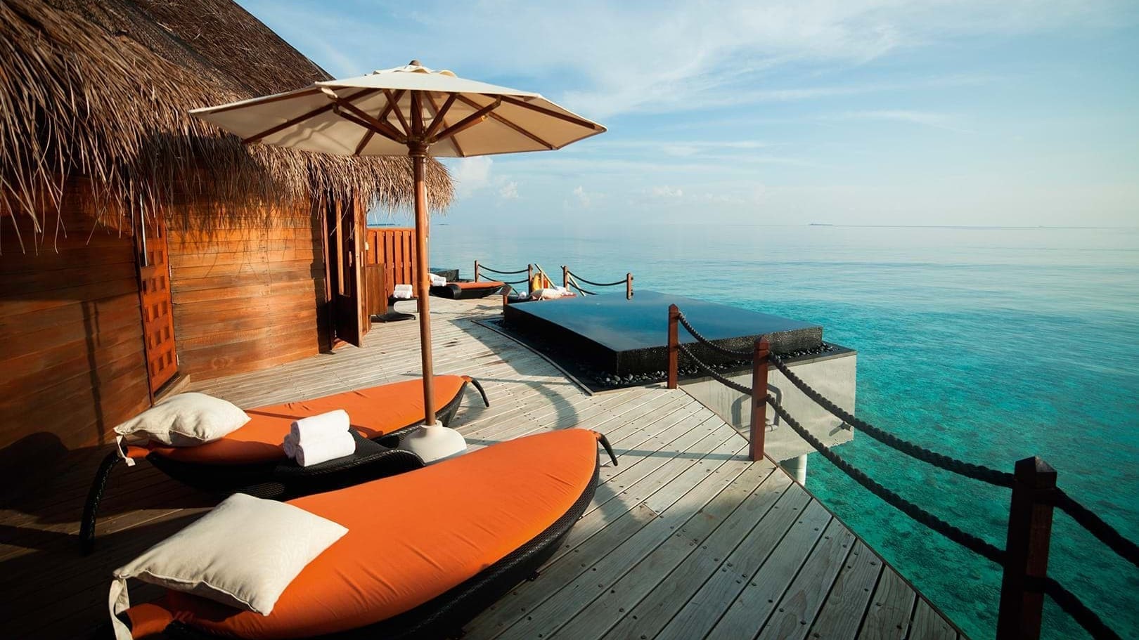 Suite with orange sunbed and infinity pool at Constance Halaveli