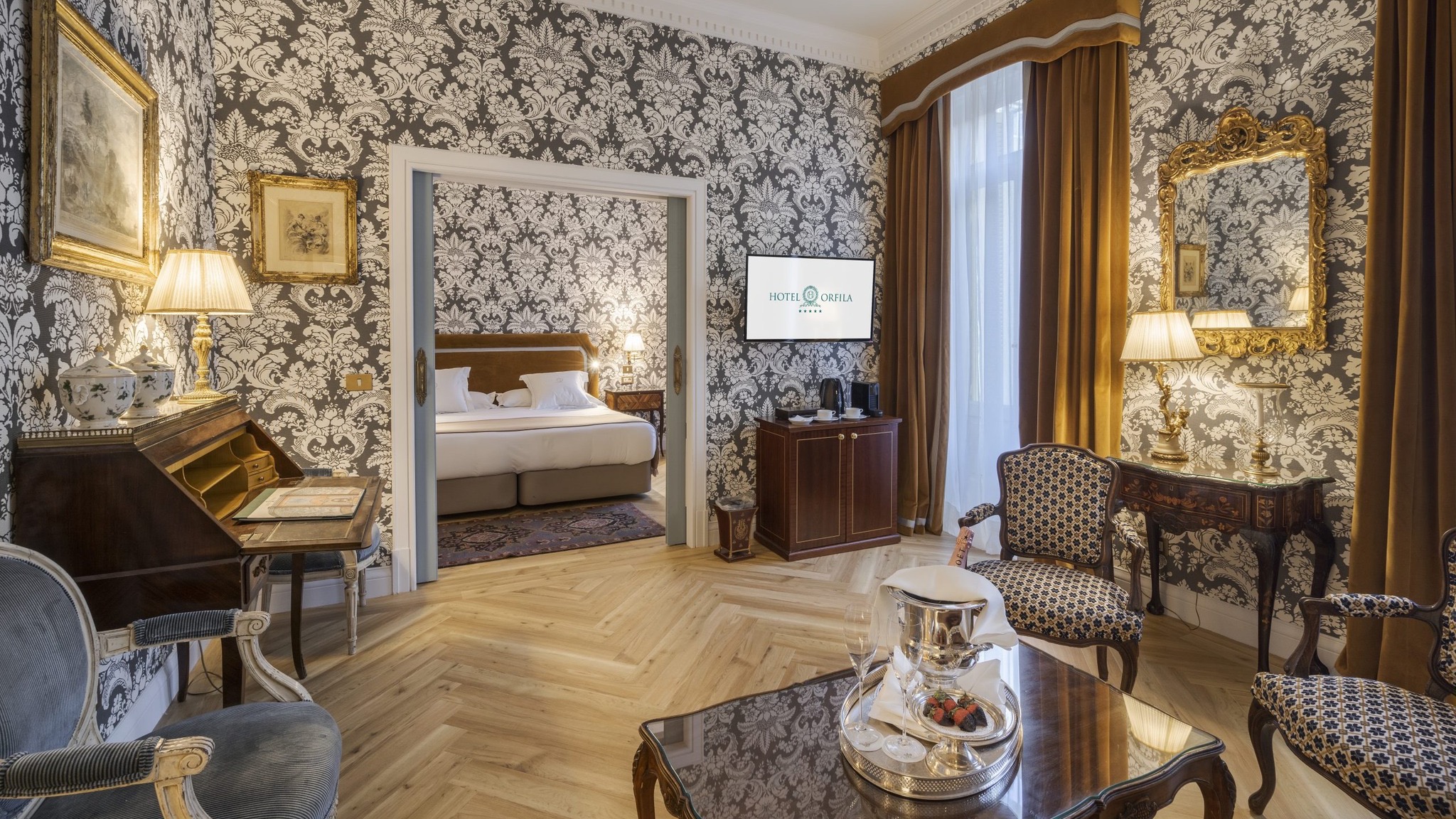 Hotel room with patter walls, wooden floor, flatscreen tv and entrance to the bedroom at Relais & Châteaux Hotel Orfila in Madrid