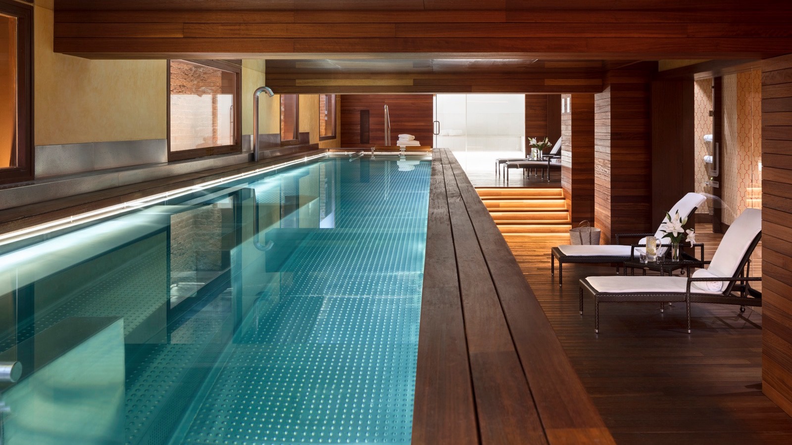 Inside hotel, long pool with wooden design and sunbeds at The URSO Hotel å Spa