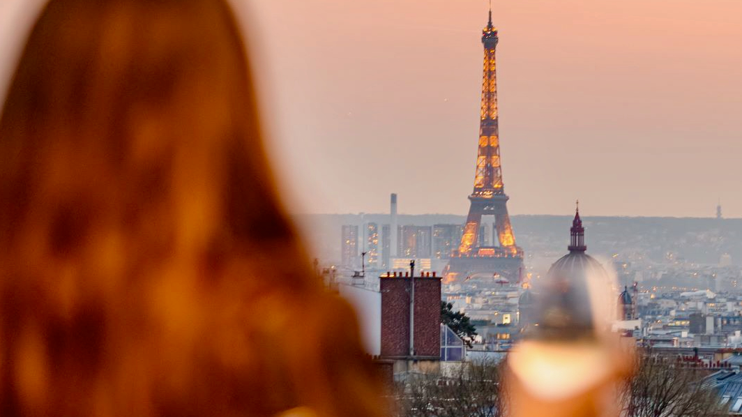 View of the Eiffel tower, behind a red haired woman at Le Rooftop, Terrass Hotel.