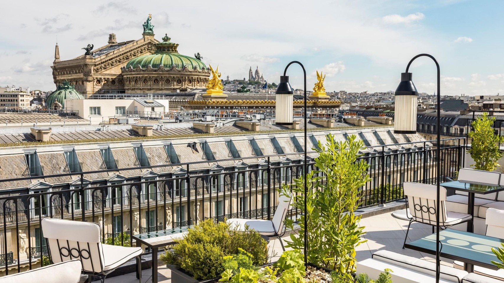 Garden uplifting rooftop, with white chair, and view to building with two golden statue. At Sewuoia - Kimpton.