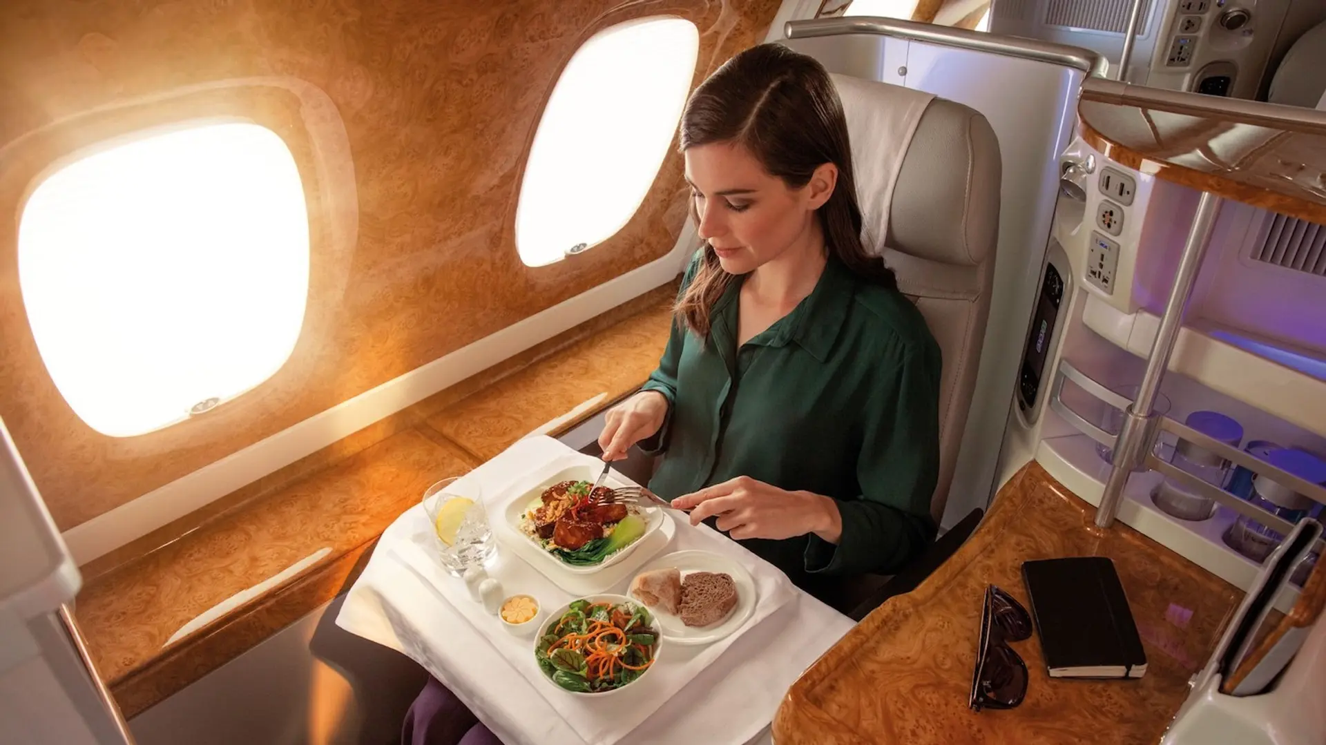 A woman in green eating food at businessclass seat