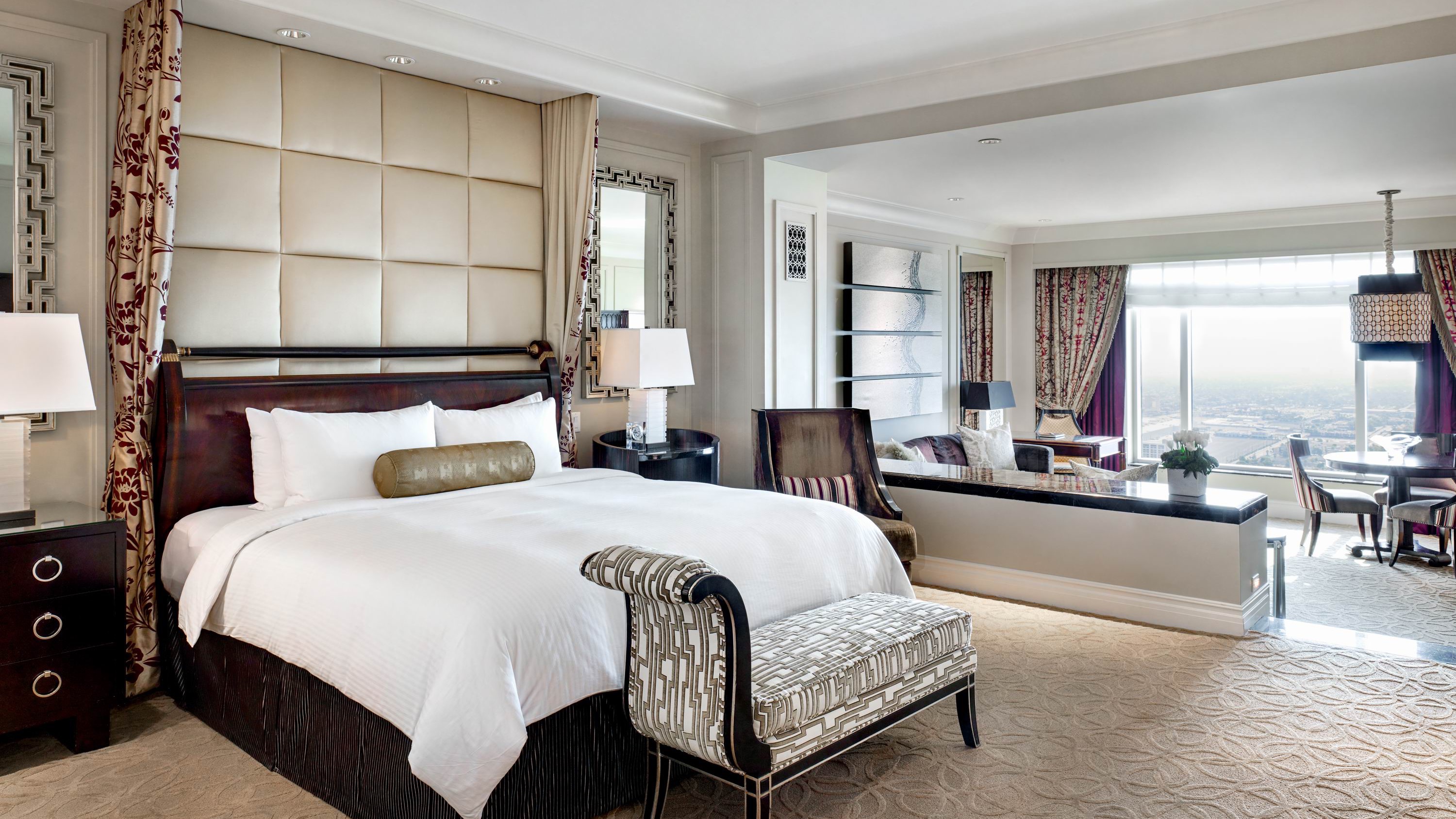 Room at The Palazzo with kingsize bed in white, light coloured furniture, sofa area and windows for view of Las Vegas.