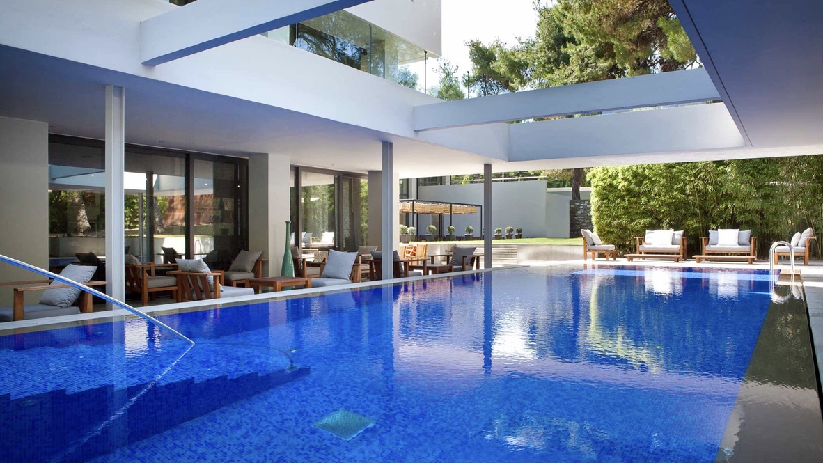Pool area with open roof, white decor and sunbeds